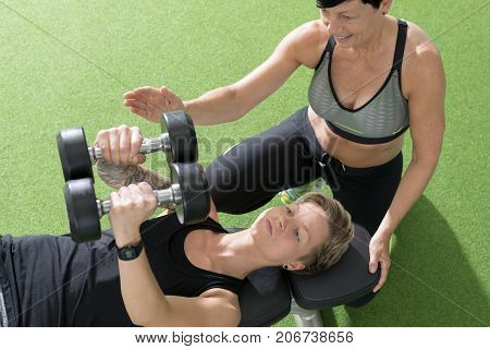 Female Personal Trainer Assists Client In Doing Chest Flyes