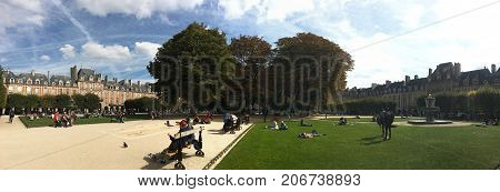 Paris France, 23 September 2017: Tourists seating in the park at Place des Vosges Paris