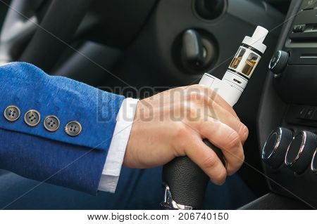 the driver's hand switches the speed of the car keep the electronic cigarette close-up