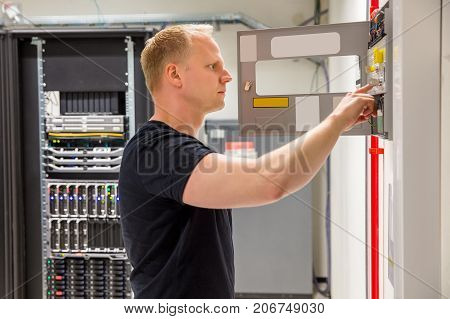 Side view of confident male technician checking fire panel in datacenter