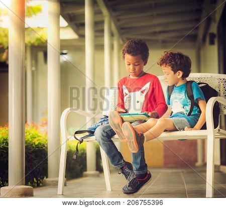 Anerican boy play game in tablet togather in the park technology outdoor computer internet concept