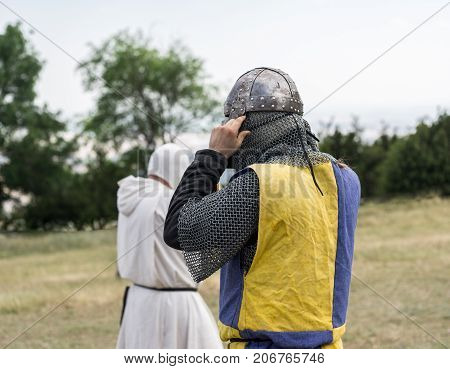 Medieval knight getting ready for battle, reenactment with costumed characters and medieval armor with chainmail, helmet swords and shields. Medieval demonstration and recreation