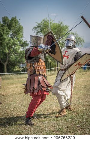 Medieval knight battle with swords and shields, reenactment with costumed characters and medieval armor with chainmail, helmet swords and shields. Medieval demonstration and recreation