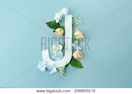 Composition with letter J and beautiful flowers on color background