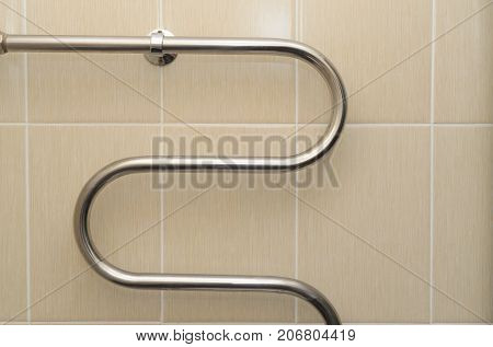 Metal curved coil in the bathroom with ceramic tiles