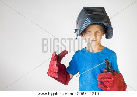Happy little kid in welder mask and welding equipment. Welding equipment welding mask protective leather gloves welding electrodes. Fun concept. Child dreaming of future profession. Career choice.