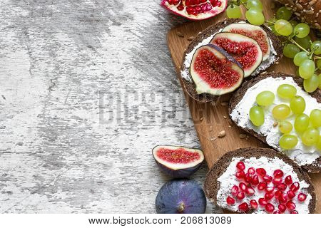 Healthy breakfast toasts. Wholegrain bread slices with cream cheese various fruit seeds and nuts on wooden cutting board. Top viee