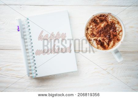 Sketchpad and cup of hot cocoa. Inscription in a notebook: Happy weekend