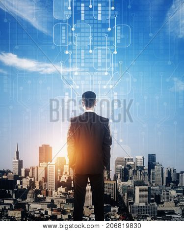 Back view of young businessman looking at city with abstract circuit board and sunlight. Future concept. Double exposure