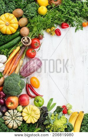 Top ivew view of fresh raw vegetables, fruits and herbs on wooden white table background, copy space for text, selective focus