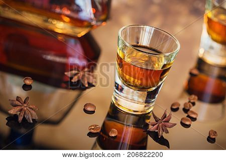 Cognac or liqueur coffee beans and spices on a glass table. Seasonal holidays concept.