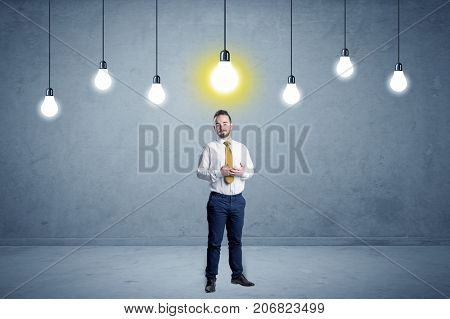 Handsome businessman in an empty space with bulbs above and uninspired face