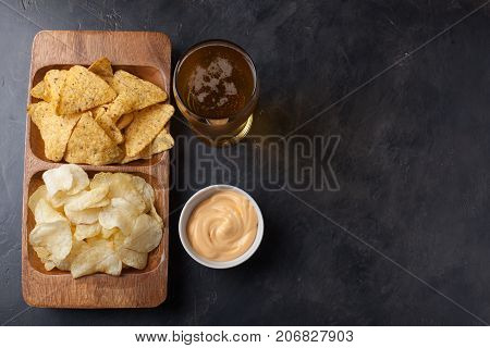 Beer In Glasses Closeup On The Concrete Table. Beer And Snacks Are Chips And Nachos In Wooden Bowl W