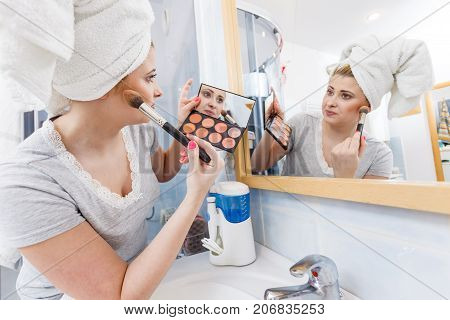 Woman In Bathroom Applying Contour Bronzer On Brush