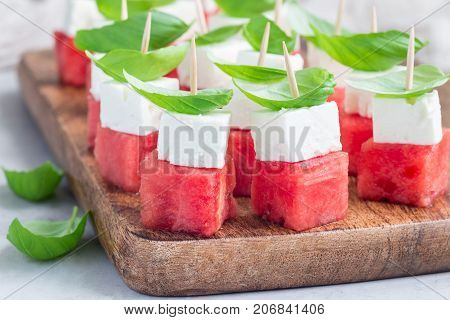 Watermelon salad or caprese with watermelon feta and basil on a wooden board horizontal
