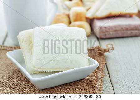 Bread in plate and coffee cup on wooden floor.