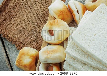 Many of bread on a wooden tray and sack.