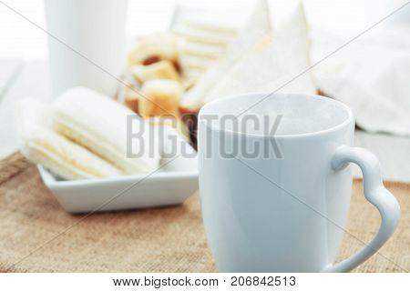 White cup of coffee and bread on the table.