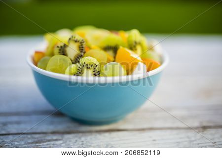 Delicious fruit salad in a bowl on a table in the garden.