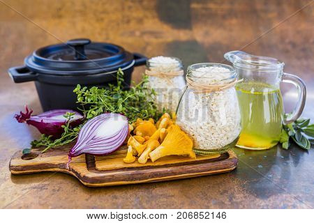 Ingredients for preparing risotto, Italian food. Fresh chanterelle mushrooms with arborio and herbs.