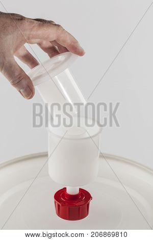 Home brewer placing airlock on beer fermentation bucket.