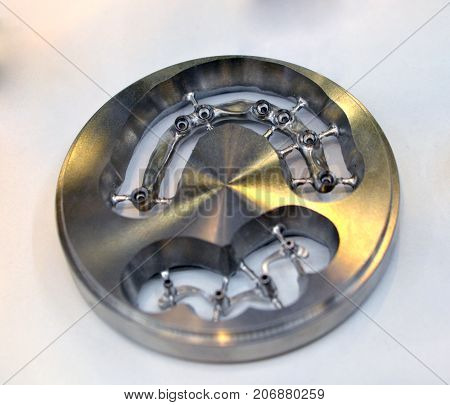 Disc CAD CAM dental machinery for milling prosthesis and crowns with a cut out bridge for implants close-up