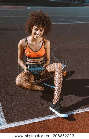 African-american Woman On Longboard With Tablet