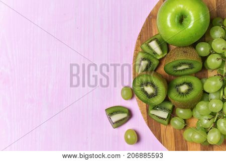 composition of kiwi, grape and apple on a pink background