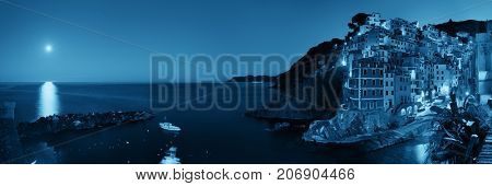 Riomaggiore waterfront view with buildings and moonset in Cinque Terre at night panorama, Italy.
