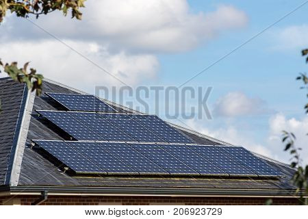 Solar panels on slate tiled roof of modern house Renewable energy technology installation on domestic building.