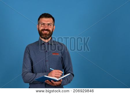 Textbook In Blue Color In Guys Hands On Blue Background