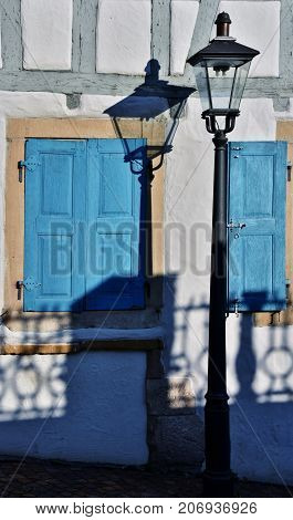 Close up of a Street lamp with its shadow on the house wall
