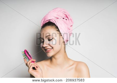 smiling girl with a towel on her head holding a comb on a white background