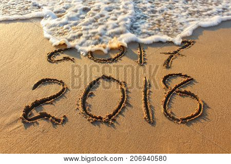 2018 year written on sandy beach sea. Inscription 2017 washes off wave.