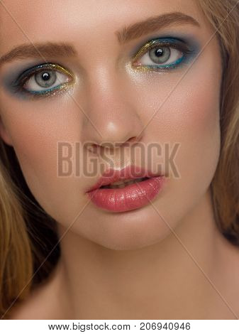 The beautiful charming blonde with an evening make-up on a face. Fashionable color cosmetics careful face care. Cosmetology fashion Spa cosmetics