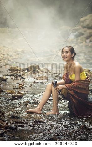 A beautiful Village women sitting and washing the clothes at the stream of waterfall or river countryside and Folkways concept