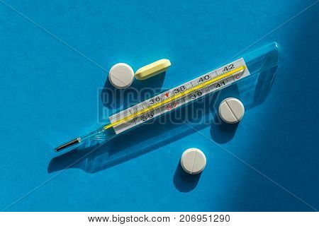 Mercury Thermometer And Pills Against The Flu On A Blue Background