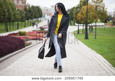 Young brunette woman in gray woolen coat on background autumn park