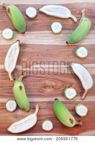 Green cultivated banana and piece of slices on wooden background