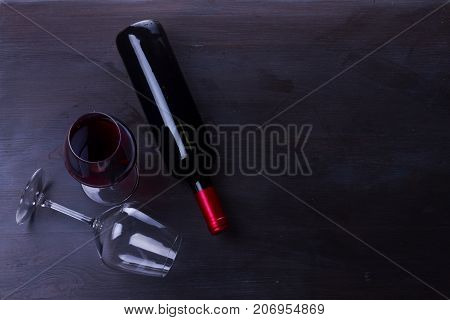 Bottle of red wine and one wine glasses on table with copy space