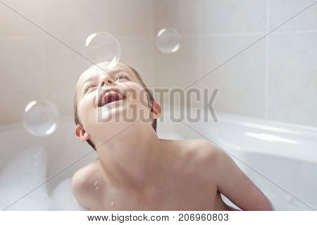 Boy playing with soap bubbles in a foam bath