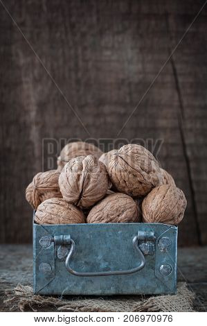 Walnuts in a small iron box and a canvas napkin. Wooden background.