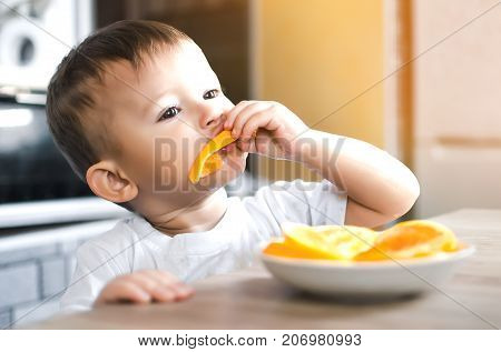 The Child In The Kitchen Eating An Orange