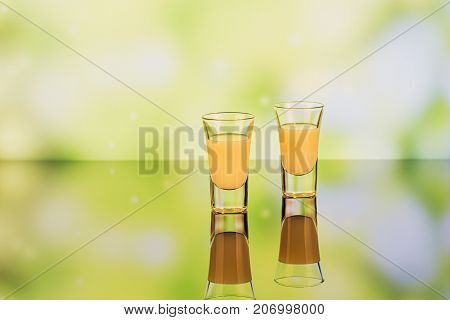 Glasses of cream liqueur on green background with reflection. Short of lemon liqueur. Traditional Italian alcoholic beverage Limoncello