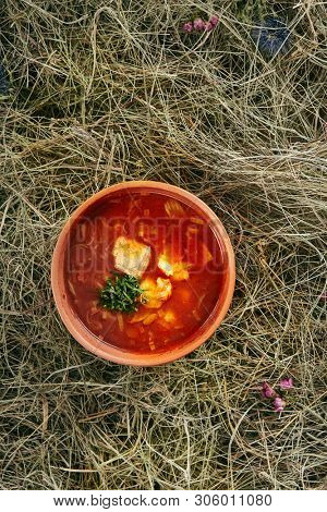 Beautiful Serving Vintage Ceramic Bowl of Red Fish Soup with Salmon and Pike Perch. Traditional Homemade Ukha, Bouillabaisse or Halaszle with Tomatoes and Vegetables on Rustic Background
