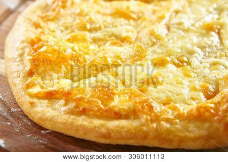 Megrelian Khachapuri Made From a Delicious Tender Dough with Melted Burnt Imeretian Cheese and Butter Close Up. Traditional Most Common Circular Hachapuri Topped with Lots of Grated Cheeses