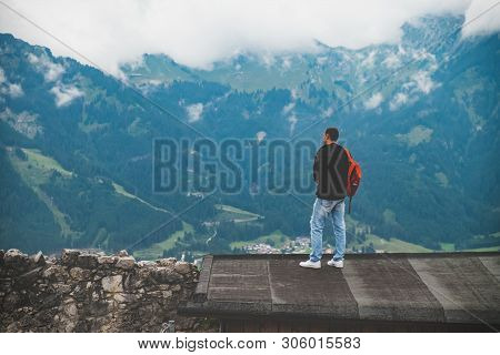 Man Is Standing On The Roof And Looking To Mountains