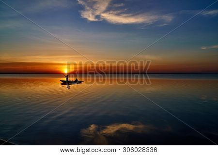 Beautiful Sunset With A Fishing Boat And Reflection Of Clouds In The Water