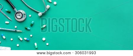 Pills And Medical Equiupments Including Stethoscope, Syringe And Scissors At Border On Green Banner 