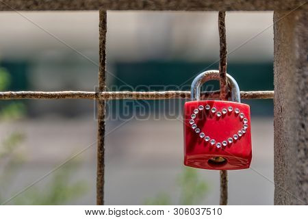 Red Padlock With A Hart Shape Made Of Small Crystals Hanging Locked On The Fence Symbolizing Love.